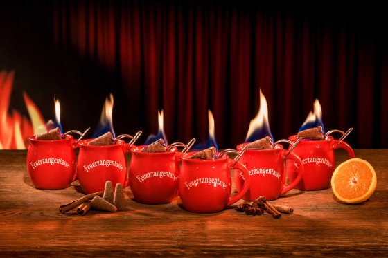 Zu sehen sind 6 rote Feuerzangentassen mit einem brennenden Zuckerhut