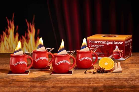 Zu sehen ist Feuerzangen 4er Set in rot. Beide Tassen sind mit der Feuerzangentassenbowle befüllt und mit einem brennenden Zuckerhut bestück